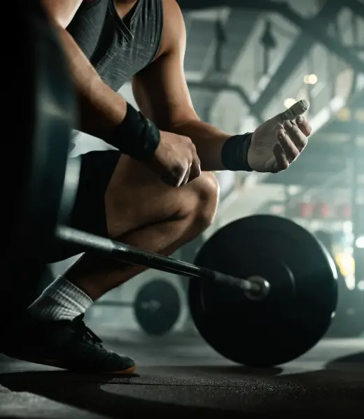 Foto realista tomada con un iPhone de una persona (hombre o mujer) realizando un ejercicio de fuerza clásico (remo con mancuerna, press o sentadilla), con técnica cuidada y postura sólida. Gimnasio real, ropa deportiva sencilla, expresión concentrada. Iluminación natural, encuadre limpio y estable. Imagen potente pero realista, sin exageraciones, sin aspecto de foto profesional.